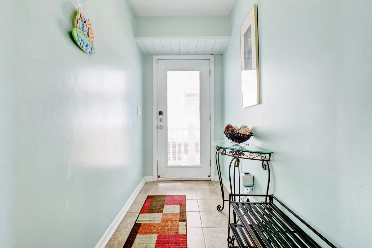 A welcoming entryway showcasing a front door, a decorative rug, and a table for setting down bags or keys. It presents a transitional space that instantly sets a cozy and organized tone upon arrival.