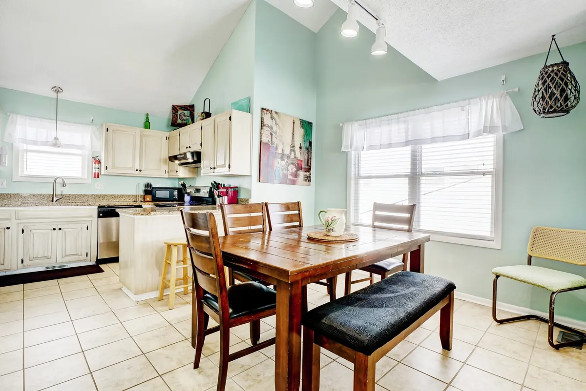 A stylish dining area and adjacent kitchen counter, complete with bar stools, decorative wall art, and a large window letting in natural light. This space is ideal for family meals, brunches, and casual gatherings, reinforcing the home’s warm and welcoming vibe.