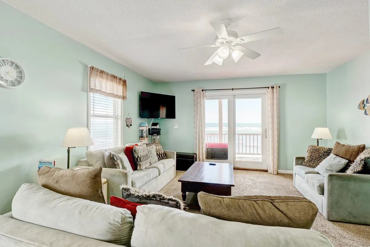 A cozy living area featuring comfortable sofas positioned to take advantage of large windows overlooking the ocean. The coffee table at the center creates a welcoming space for socializing, relaxing, or enjoying movie nights with friends and family.
